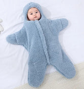Baby in a blue fluffy snowsuit lying on a white blanket