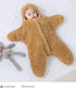 Baby in a brown fleece snowsuit lying on a white surface with a gray plush toy.