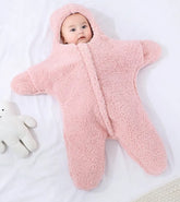 Baby in a pink fleece snowsuit lying on a white surface