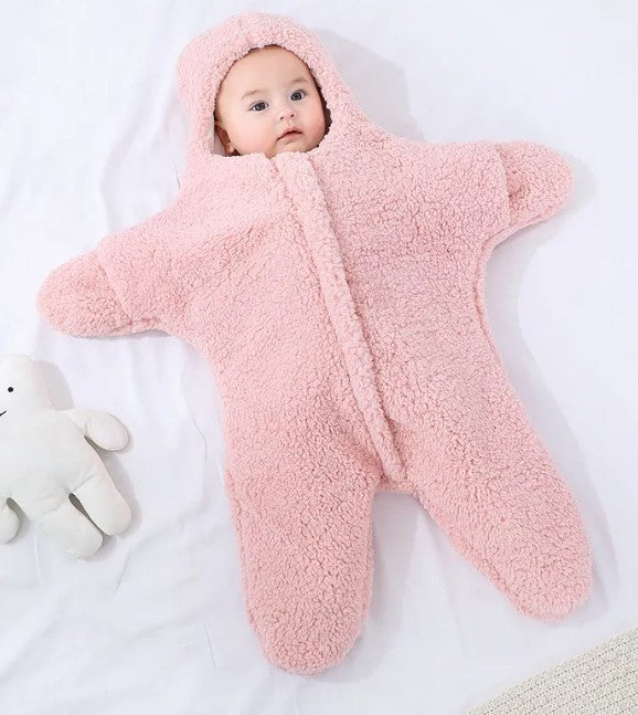 Baby in a pink fleece snowsuit lying on a white surface