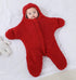 Baby in a red fuzzy onesie lying on a white surface