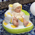 Baby sitting in a green and white inflatable pool seat with lemon designs, wearing a matching hat, on a tiled pool deck.