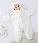 Baby wrapped in a white blanket on a light gray background