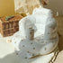 White inflatable baby seat with floral patterns on a textured surface.