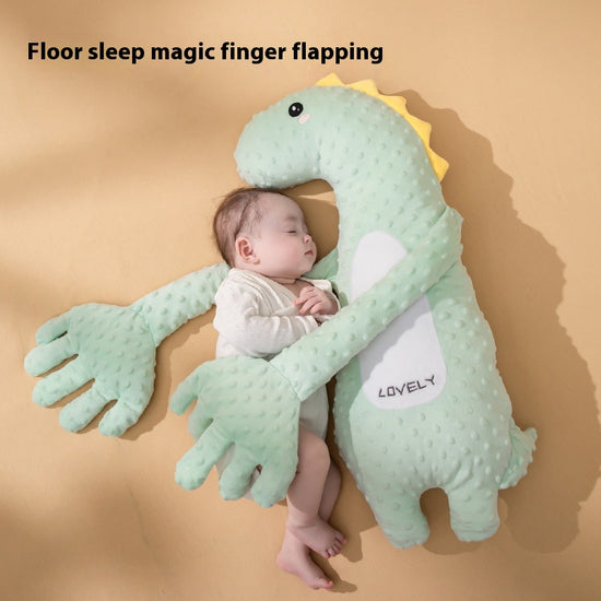 Baby lying on a green dinosaur-shaped pillow with &